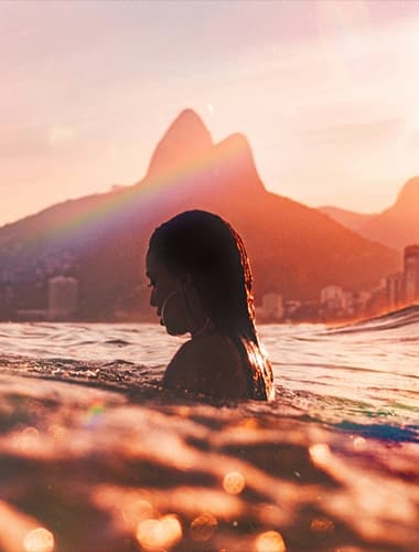 mulher no mar do Rio de Janeiro, com a maior parte do corpo submersa e apenas os ombros e a cabeça para fora da água